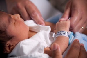 Parents holding newborn baby in hospital.